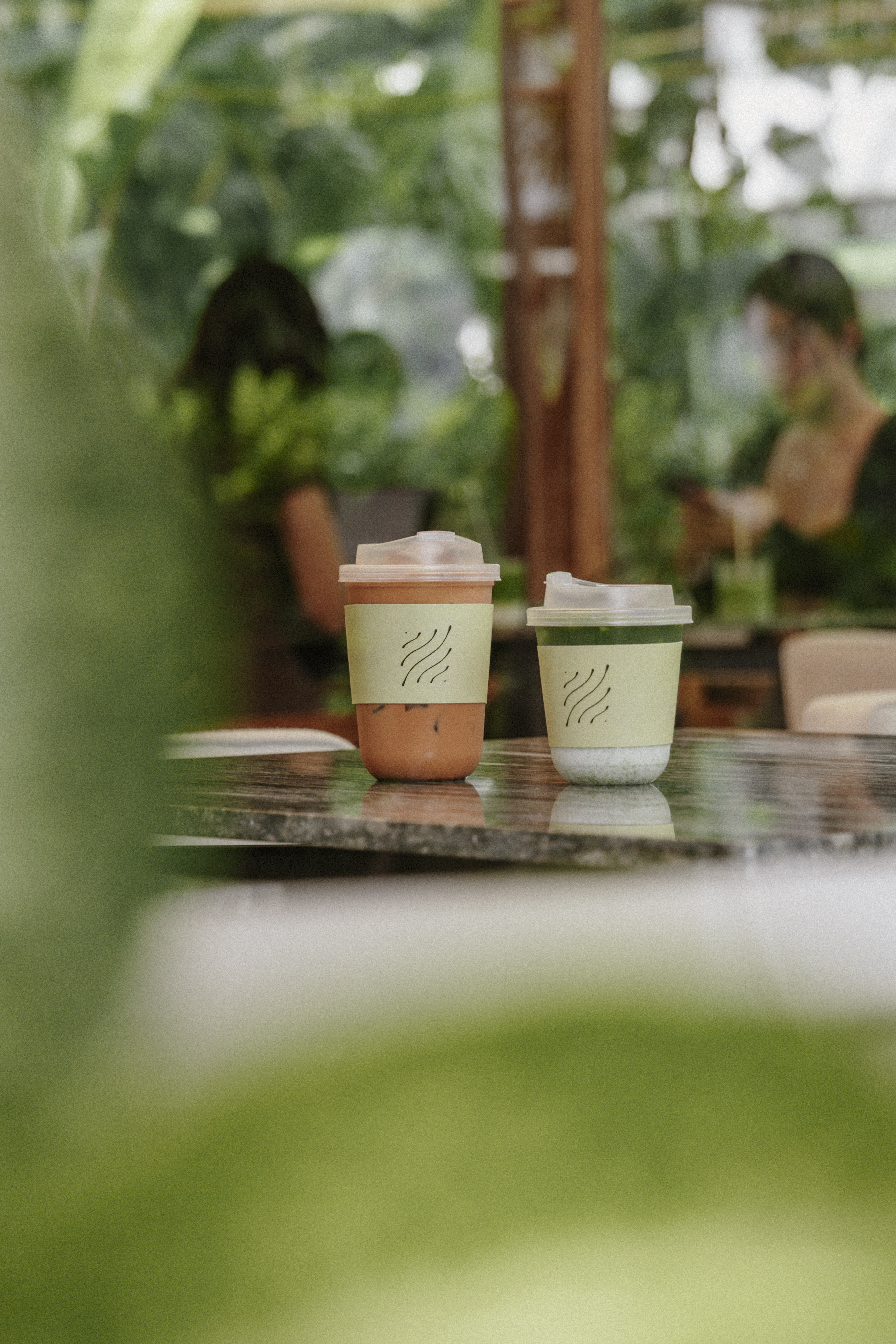 LOM signature cups on marble, customers in garden behind